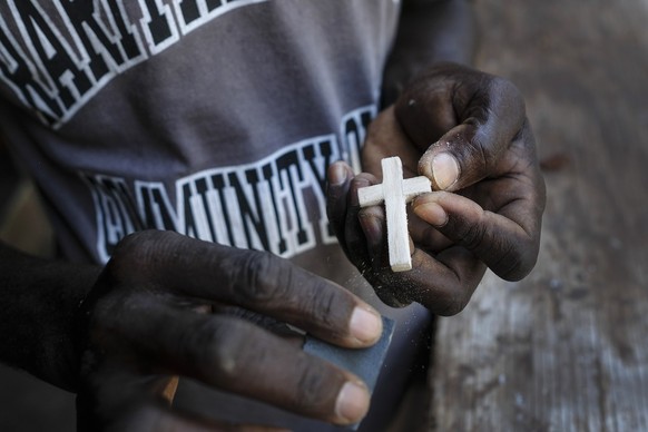 A worker of the rectory of the Societe des pretres de Saint Jacques, where Catholic priest Jean-Nicaisse Milien is staying, sands a wooden cross, in Port-au-Prince, Haiti, Tuesday, Nov. 9, 2021. Fathe ...