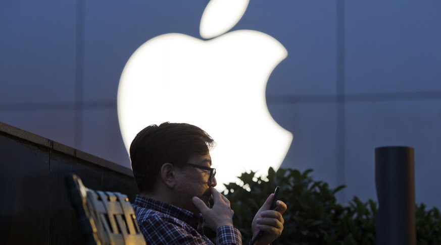 FILE - In this Friday, May 13, 2016 file photo, a man uses his mobile phone near an Apple store logo in Beijing, China. A Beijing court said in an online statement Thursday, June 30, 2016, that Apple  ...