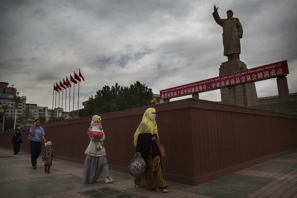 Verschleierte Musliminnen vor einer Mao-Statue in Kaschgar.