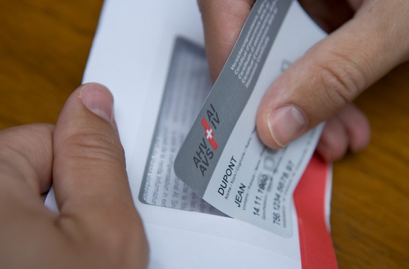 A man takes a prototype of the new insurance certificate of the AHV-IV (AHV: Federal old-age and bereaved people insurance/IV: Disabled people insurance) with the name of the insured party, the date o ...