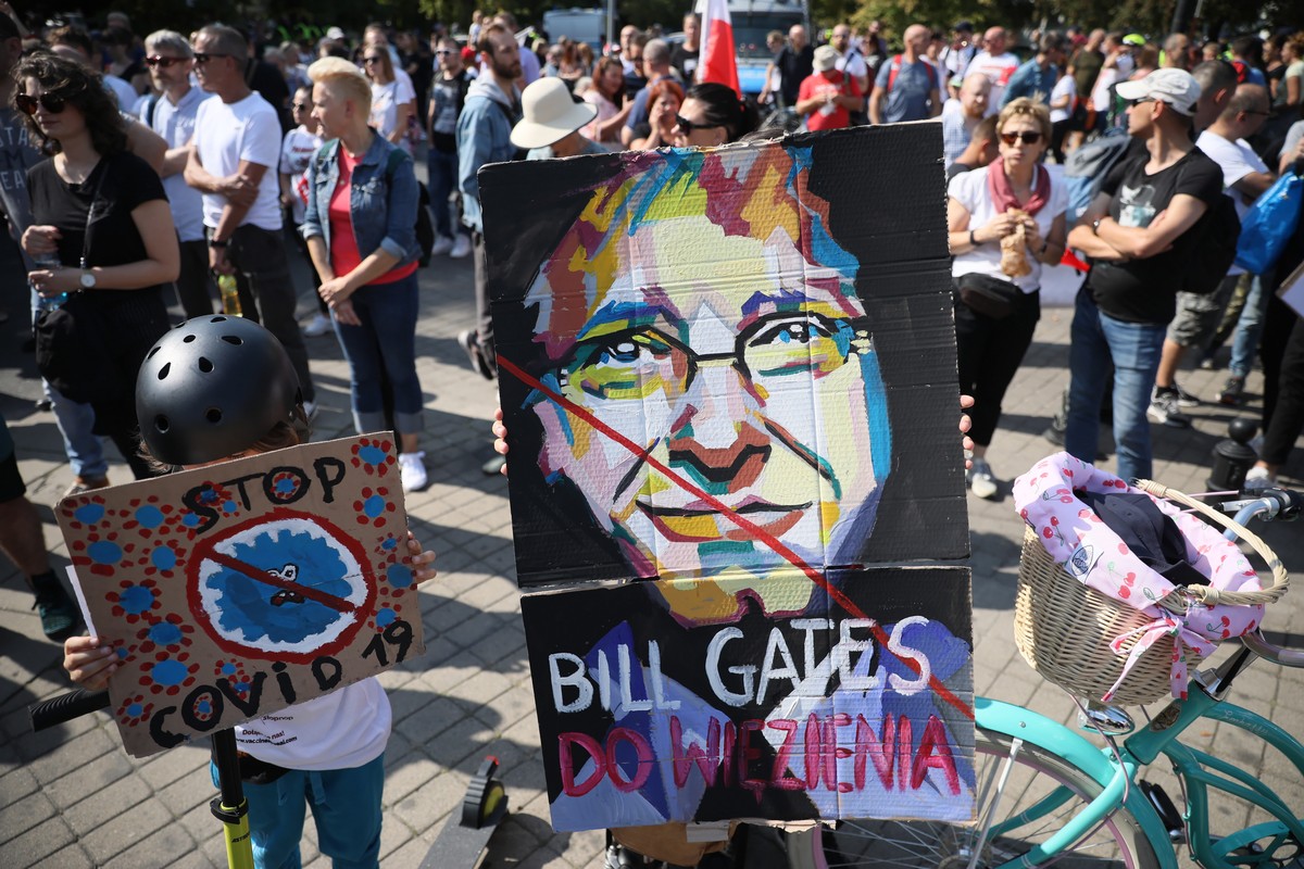 epa08663422 People with a banner showing Bill Gates and words 'Go to Prison' take part in the 'End the Pandemic' march in the center of Warsaw, Poland, 12 September 2020. People de ...
