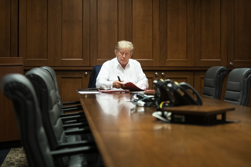 In this image released by the White House, President Donald Trump works in his conference room at Walter Reed National Military Medical Center in Bethesda, Md., Saturday, Oct. 3, 2020, after testing p ...