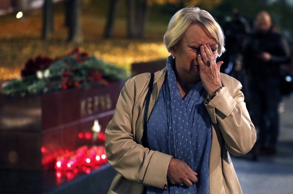 epa07100395 A Russian woman reacts as flowers and candles lay on the monument to the hero-city of Kerch in the Alexander Garden as a sign of mourning for the dead children at a vocational school in Ke ...