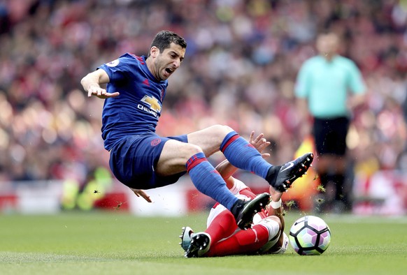 Manchester United&#039;s Henrikh Mkhitaryan goes to ground after a challenge from Arsenal&#039;s Alex Oxlade-Chamberlain, rear on ground, during the English Premier League match Manchester United agai ...