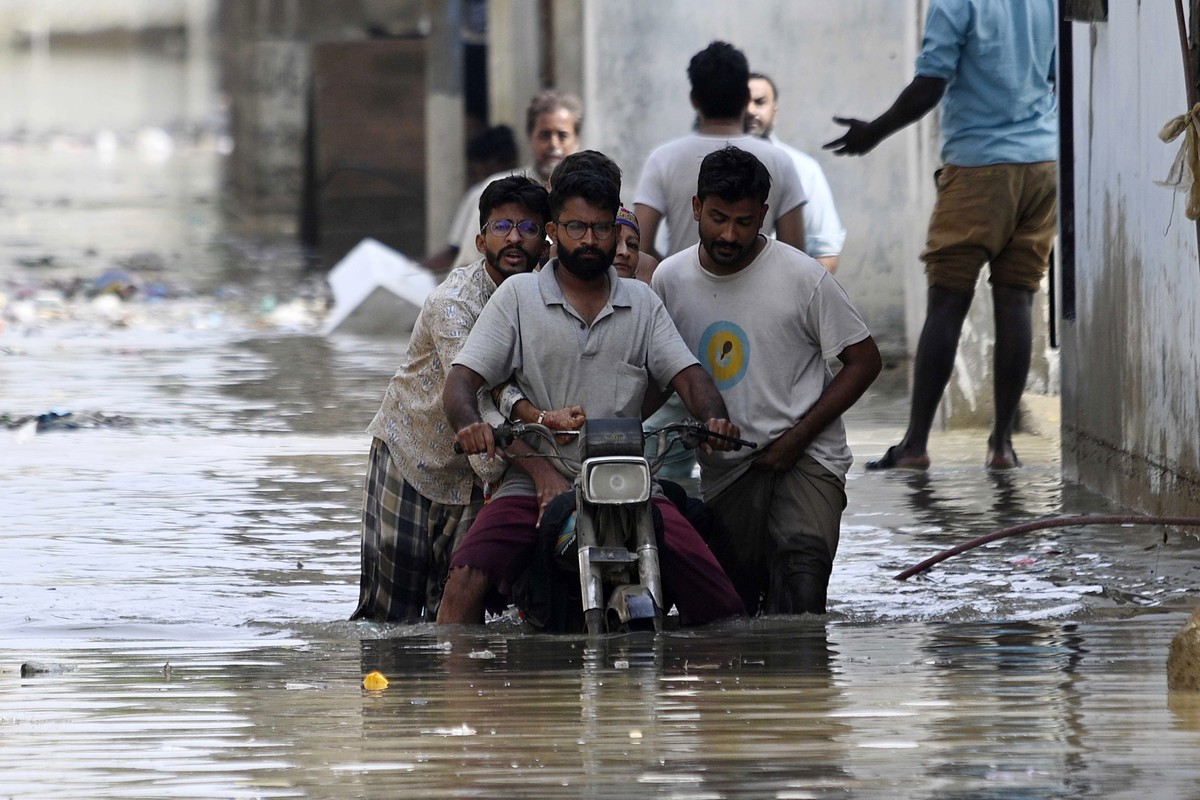 epa12311899 People wade through rainwater after torrential rains in Karachi, Pakistan, 20 August 2025. Since the start of the monsoon season on 26 June, the death toll from rains and flooding in Pakis ...