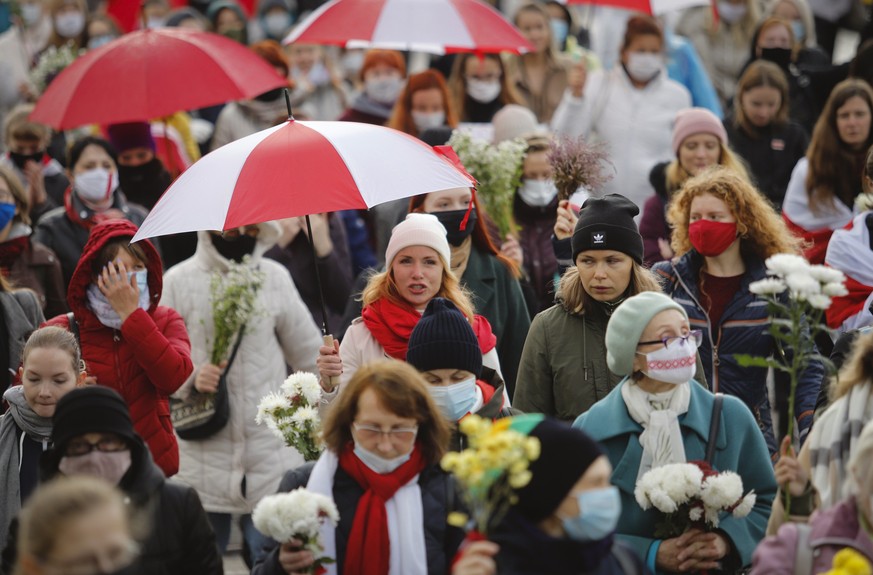 Belarusian women with umbrellas in the colors of the old Belarusian national flag take part in an opposition rally to protest the official presidential election results in Minsk, Belarus, Saturday, Oc ...