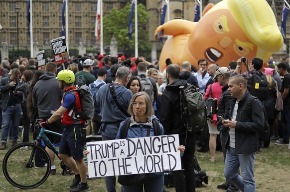 A woman holds a placard as the &#039;Trump Baby&#039; blimp is inflated in Parliament Square in central London as people start to gather to demonstrate against the state visit of President Donald Trum ...