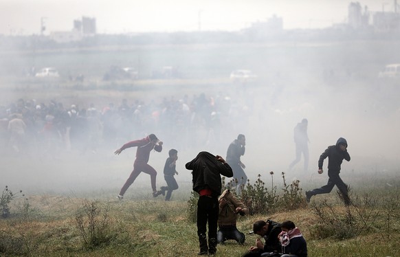 epa06637416 Palestinians protesters run for cover from Israeli tear-gas during clashes after protests along the border between Israel and Gaza Strip, in the eastern Beit Hanun town, in the northern Ga ...