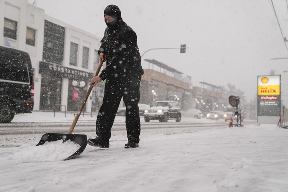 A man shovels a pavement during snowfall in Agios Steganos, north of Athens ,on Monday, Jan. 24, 2022. The wave of bad weather hitting Greece is forecast to continue through Tuesday, and has seen snow ...