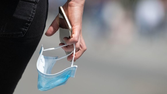 27.05.2020, Baden-Württemberg, Stuttgart: Eine Passantin hält auf der Königstraße einen Mund-Nasen-Schutz und ein Smartphone in der Hand. Die CDU-Spitzenkandidatin für die Landtagswahl in Baden-Württe ...