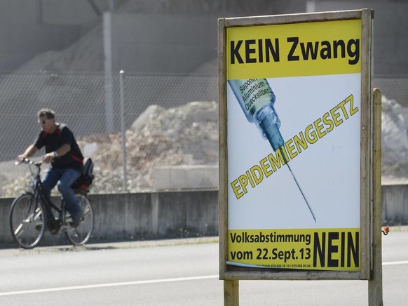 Ein Abstimmungsplakat thematisiert die Revision des Epidemiengesetzes, am Dienstag, 3. September 2013, in Pfungen. Am 22. September 2013 stimmt das Volk ueber die Revision ab. (KEYSTONE/Steffen Schmid ...