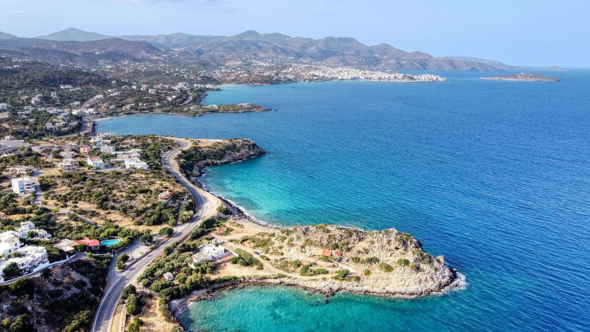 Dans le lointain et bordant des eaux turquoises, la ville d'Ágios Nikólaos.