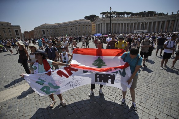 Faithful hold up a Lebanese flag as Pope Francis delivers his speech during the Angelus noon prayer he delivers from the window of his studio overlooking St. Peter's Square at the Vatican, Sunday, Aug.9, 2020. Pope Francis has renewed his appeal for unity within Lebanon and for help from abroad as the nation reels from last week's devastating explosion in Beirut's port. (AP Photo/Alessandra Tarantino)