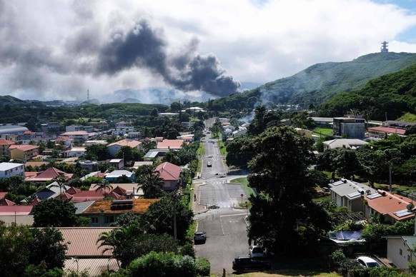 Smoke rises in the distance in Noumea on May 14, 2024, amid protests linked to a debate on a constitutional bill aimed at enlarging the electorate for upcoming elections of the overseas French territo ...