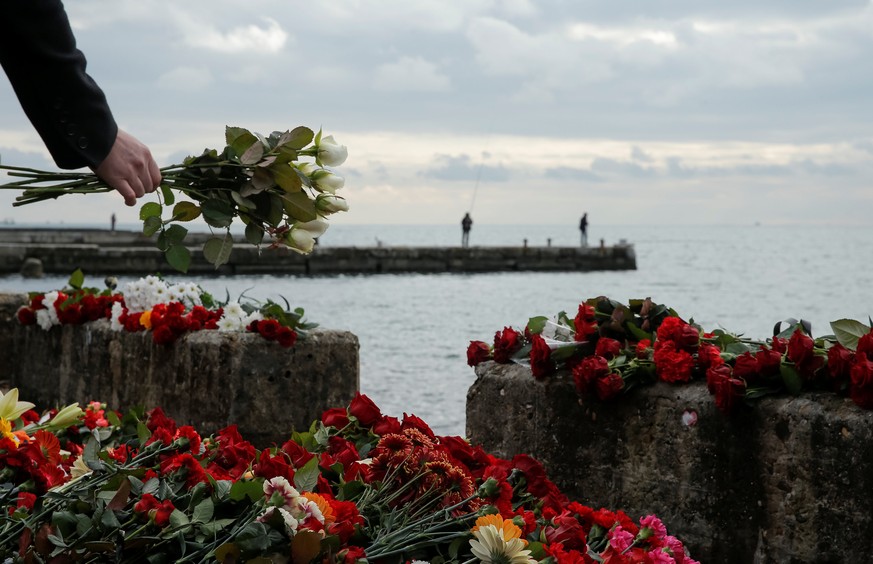 A person lays flowers in memory of passengers and crew members of Russian military Tu-154, which crashed into the Black Sea on its way to Syria on Sunday, at an embankment in the Black Sea resort city ...