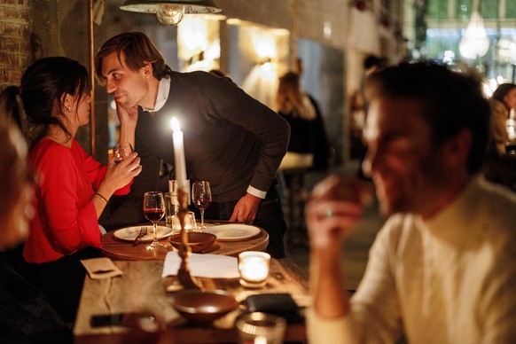 A couple speak as they enjoy a drink and candle lit dinner at Brasserie Surrealiste in Brussels, Wednesday, Sept. 28, 2022. A group of restaurant owners in Brussels has imagined how a future without g ...