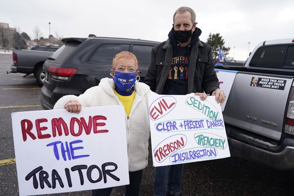 Roz Heise, left, and Greg Eisler display placards during a gathering calling for the impeachment of President Donald Trump at South High School before a car rally through the streets of downtown Sunda ...