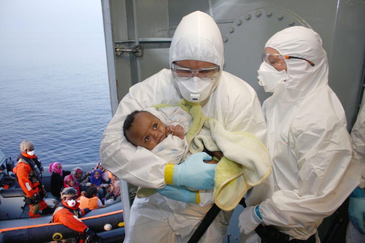 epa04749834 A handout photo provided by the German Armed Forces (Bundeswehr) on 15 May 2015 of German navy personnel taking care of a rescued woman and her baby aboard the German Navy frigate 'He ...