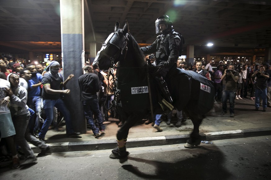 Mit einem Pferd versucht ein Polizist, die Masse zurückzuhalten.