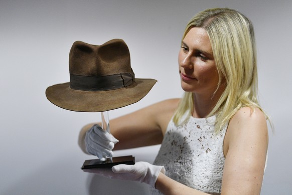 epa07000517 A woman poses with a Indiana Jones hat from the film Raiders of the Lost Ark at a media preview for at television and film memorabilia auction by Prop Store. in London, Britain, 06 Septemb ...