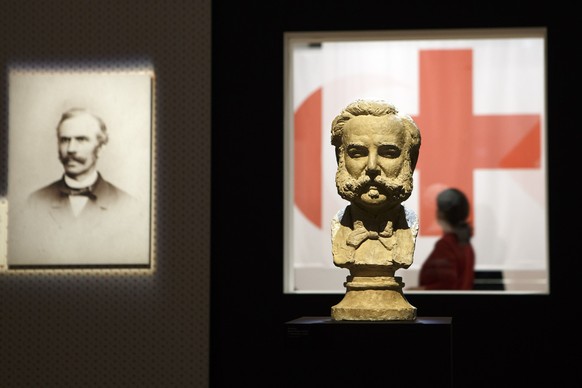 A visitor passes by the ICRC (International Committee of the Red Cross) emblem behind a bust of Henri Dunant, founder of the Red Cross, during a preview of the exhibition &quot;Humanizing War? The ICR ...