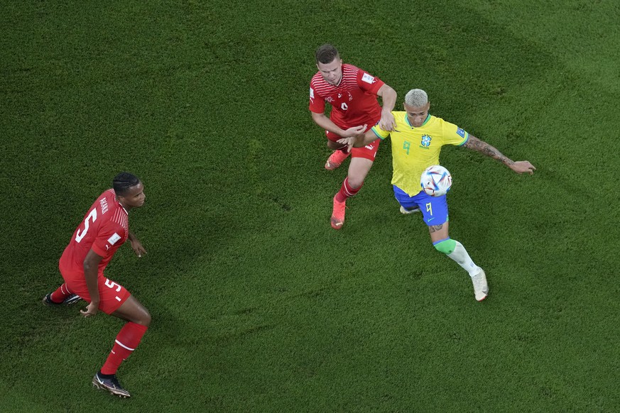 Brazil's Richarlison, right, challenges for the ball with Switzerland's Nico Elvedi, center, as Switzerland's Manuel Akanji looks them during the World Cup group G soccer match between Brazil and Swit ...
