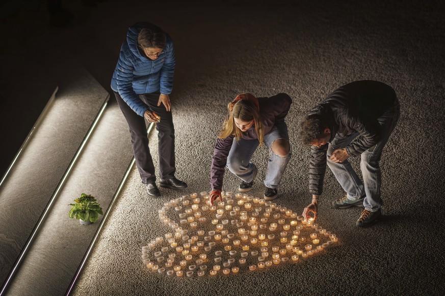 People light candles as they attend a ceremony following the discovery of 5 ski tourers who had died near Tete Blanche in the Swiss alps mountains, in Vex, Switzerland, Monday, March 11, 2024. Five cr ...