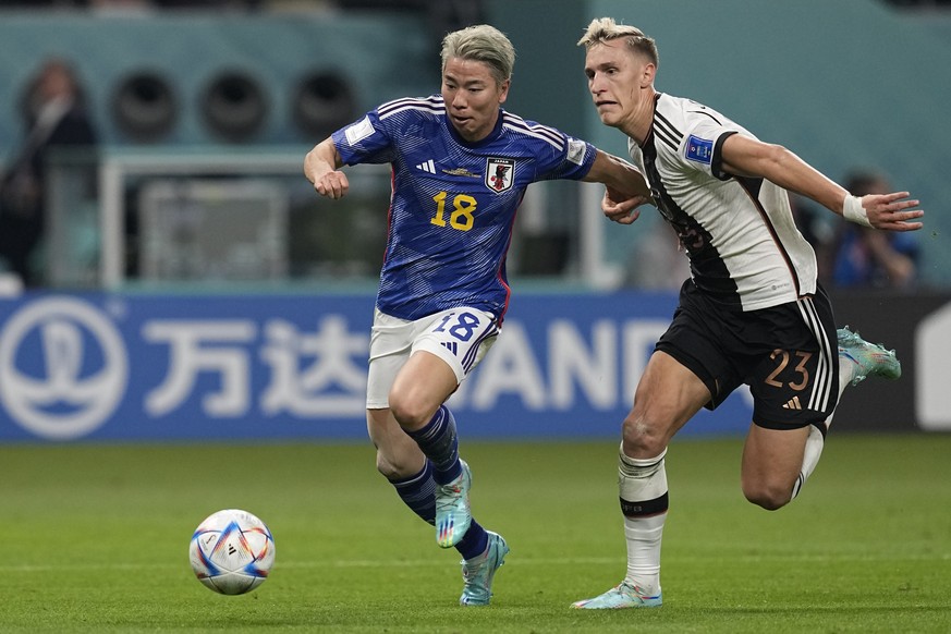 Japan&#039;s Takuma Asano, left, fights for the ball with Germany&#039;s Nico Schlotterbeck, on his way to score his side&#039;s second goal during the World Cup group E soccer match between Germany a ...