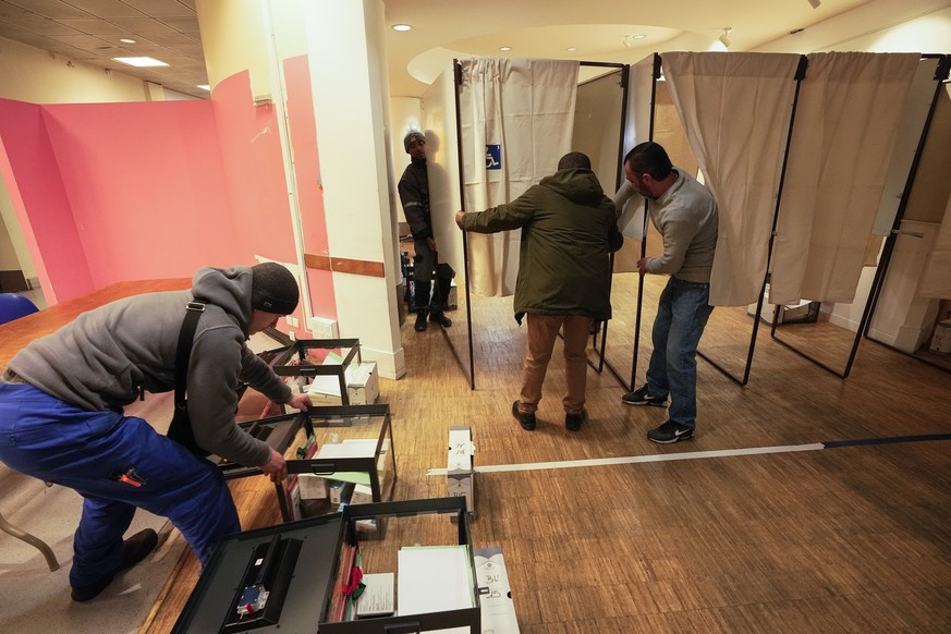 A municipality worker pushes a ballot box as team workers setting up a voting booth at a polling station in Montreuil, east of Paris, Saturday, April 9, 2022. President Emmanuel Macron said Friday he  ...