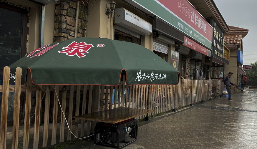 A man walks out from a mini market using a gasoline powered generator to run electric during a blackout in Shenyang in northeastern China's Liaoning Province, Wednesday, Sept. 29, 2021. People at ...