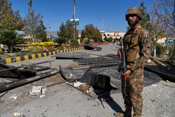 An Army soldier stands guard next to damages at the main gate of an army-run cadet college that was assaulted by militants on Monday, in Wana, a city in the northwestern Pakistani district South Wazir ...