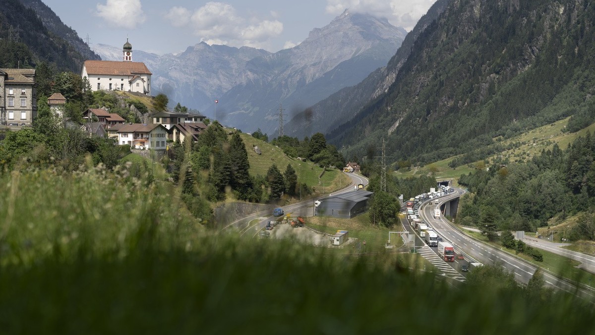 Autos und Lastwagen bilden kilometerlange Staus auf der Autobahn A2, weil die Autobahn von zwei auf eine Spur reduziert wird, um in den Gotthard-Strassentunnel zu gelangen, aufgenommen neben dem Dorf  ...
