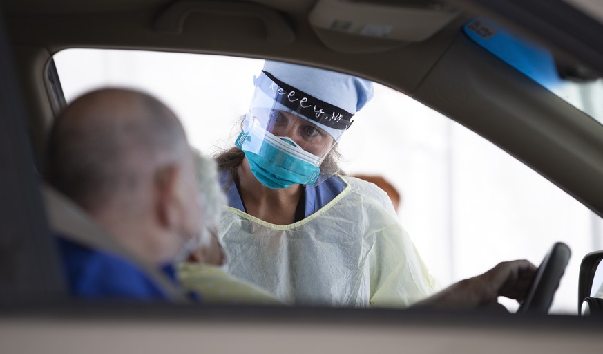 epa08572733 Nurse Practitioner Kelly Nagi of the Brockton Neighborhood Health Center, performs Covid-19 tests on drive up patients at the Brockton High School in Brockton, Massachusetts, USA 29 July 2 ...