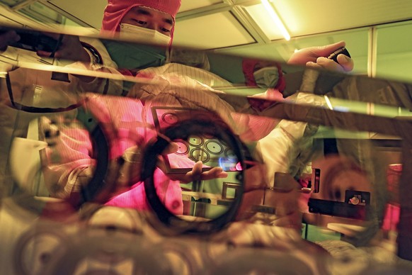 A worker checks on the optic glass at Wuhan Genuine Gaoli Optics Co., a maker of optoelectronic devices, in Wuhan in central China&#039;s Hubei province, Oct. 15, 2021. China&#039;s economic growth is ...