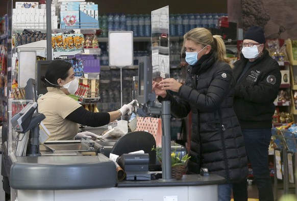 Supermarket employees and customers wear protective masks in a shop in Vienna, Austria, Wednesday, April 1, 2020. In Austria protective masks should be worn in shops from Wednesday on. The Austrian go ...