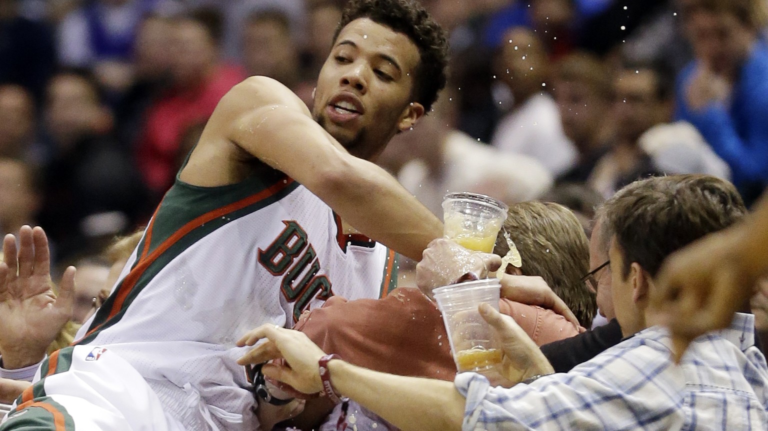 Fans spill their drinks as Milwaukee Bucks&#039; Michael Carter-Williams dives to save a ball from going out of bounds during the second half of an NBA basketball game against the Boston Celtics Wedne ...