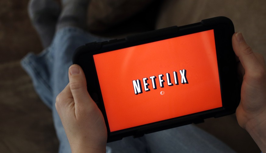 FILE - In this Friday, Jan. 17, 2014, file photo, a person displays Netflix on a tablet in North Andover, Mass. Netflix subscribers can now download shows and movies to watch later when they’re not on ...