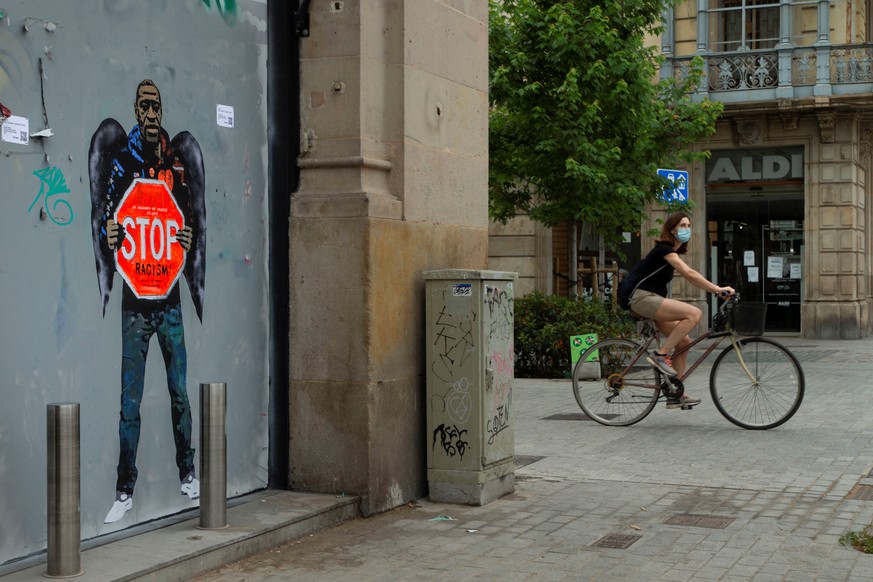 epa08458049 A cyclist rides by a graffiti to pay a tribute to late US George Floyd, by urban artist TVBOY, in Barcelona, northeastern Spain, 01 June 2020. A bystander's video posted online on 25 ...