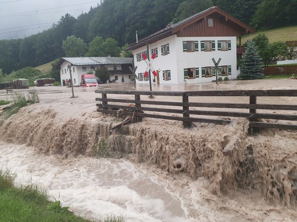 Water flows over a square in front of a house in Bischofswiesen, Germany, Saturday, July 17, 2021. The Berchtesgadener Land district has declared the situation a disaster after heavy rain caused sever ...