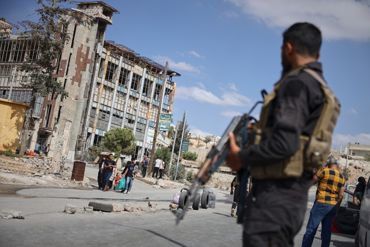 Syrian security forces stand guard as residents leave the Sheikh Maqsoud and Achrafieh neighborhoods of Aleppo, Syria, Tuesday, Oct. 7, 2025, following overnight clashes between Syrian government troo ...