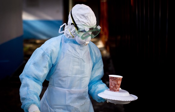 FILE - In this Oct. 8, 2014 photo, a medical worker from the Infection Prevention and Control unit wearing full protective equipment carries a meal to an isolation tent housing a man being quarantined ...