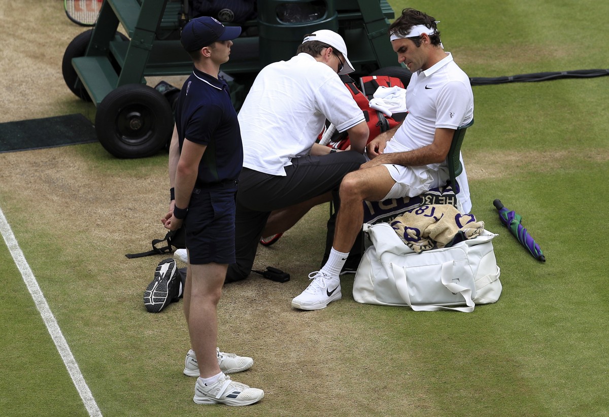 Roger Federer of Switzerland receives medical attention during a break in his men's semifinal singles match against Milos Raonic of Canada on day twelve of the Wimbledon Tennis Championships in L ...