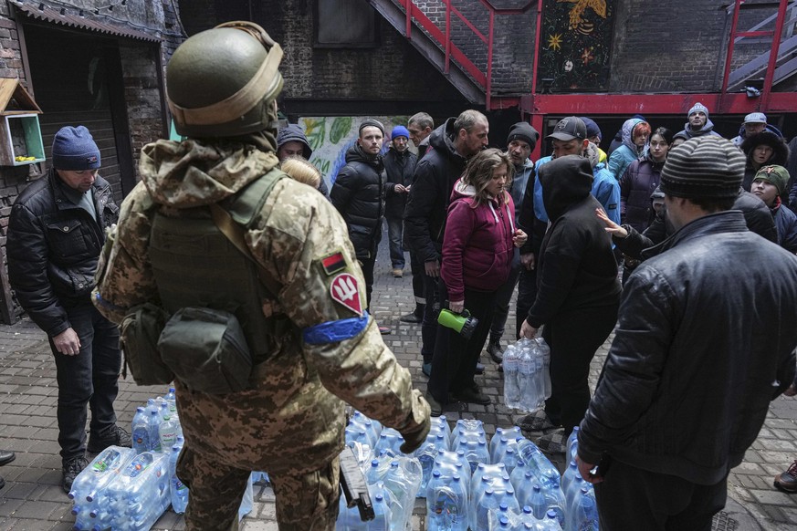 Ukrainian servicemen, center, distributes water to people in Mariupol, Ukraine, Sunday, March 6, 2022. (AP Photo/Evgeniy Maloletka)