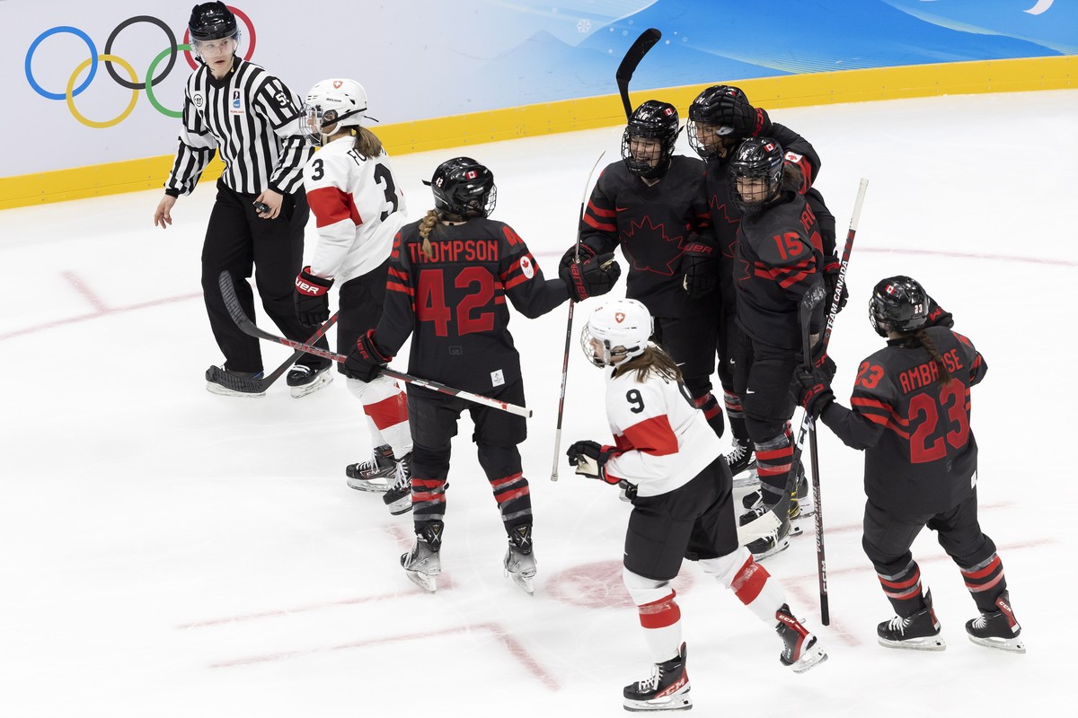 epa09724215 Canada's players celebrate their goal after scoring the 3:0, during the preliminary round game of the women's ice hockey game between Canada and Switzerland at the 2022 Olympic W ...