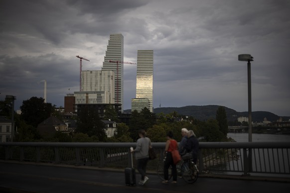 Passanten gehen ueber die Wettsteinbruecke vor dem Roche-Turm Bau 1 und 2, am Freitag, 2. September 2022 in Basel. Der 205 Meter hohe Roche Turm Bau 2 des Schweizer Pharmaunternehmens Roche Holding AG ...