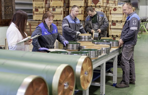 epa10568833 A handout photo made available by the Russian Defence Ministry shows employees assembling while Russian Defence Minister Shoigu (not pictured) visits ammunition production facilities in Tu ...