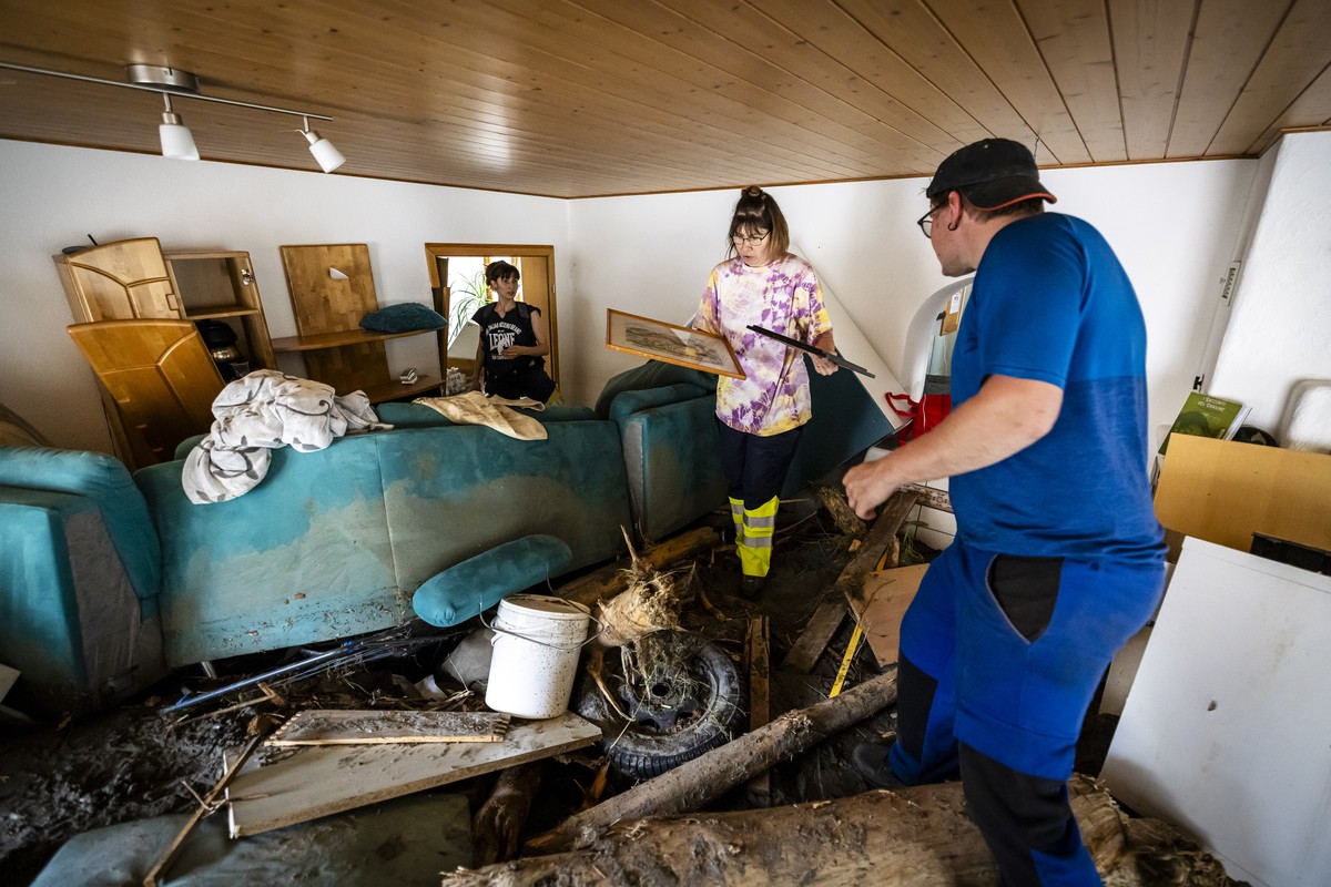 Chrisitine Biadici , center, saves diplomas next to her daughter Irina, left, and son Elia, right, in the rubble-filled living room as she returned to her house for the first time after the storm to s ...