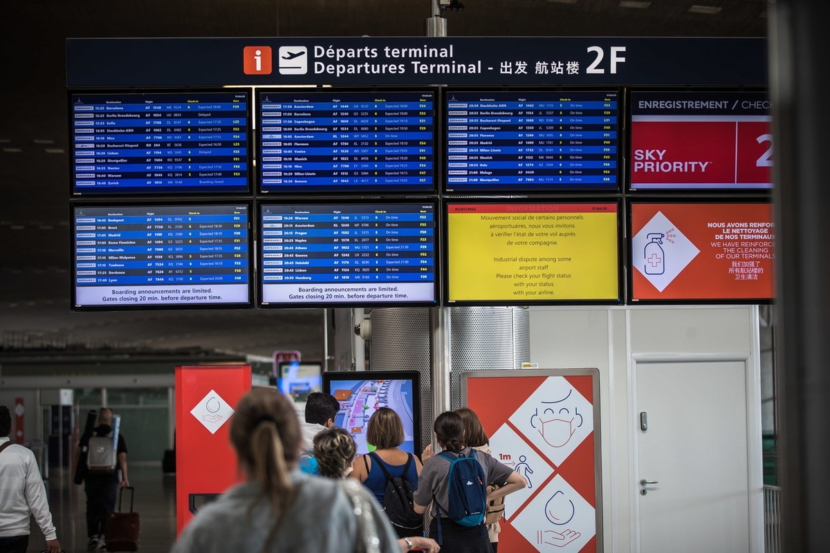 Des navetteurs regardent un panneau d'information sur les vols à l'aéroport de Roissy près de Paris, France, le 1er juillet 2022.
