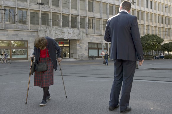 ARCHIV - ZUM SOZIALBERICHT 2016 VOM SCHWEIZER KOMPETENZZENTRUM SOZIALWISSENSCHAFTEN, FORS, STELLEN WIR IHNEN FOLGENDES BILDMATERIAL ZUR VERFUEGUNG - Eine Person in einem Anzug beobachtet eine alte Fra ...