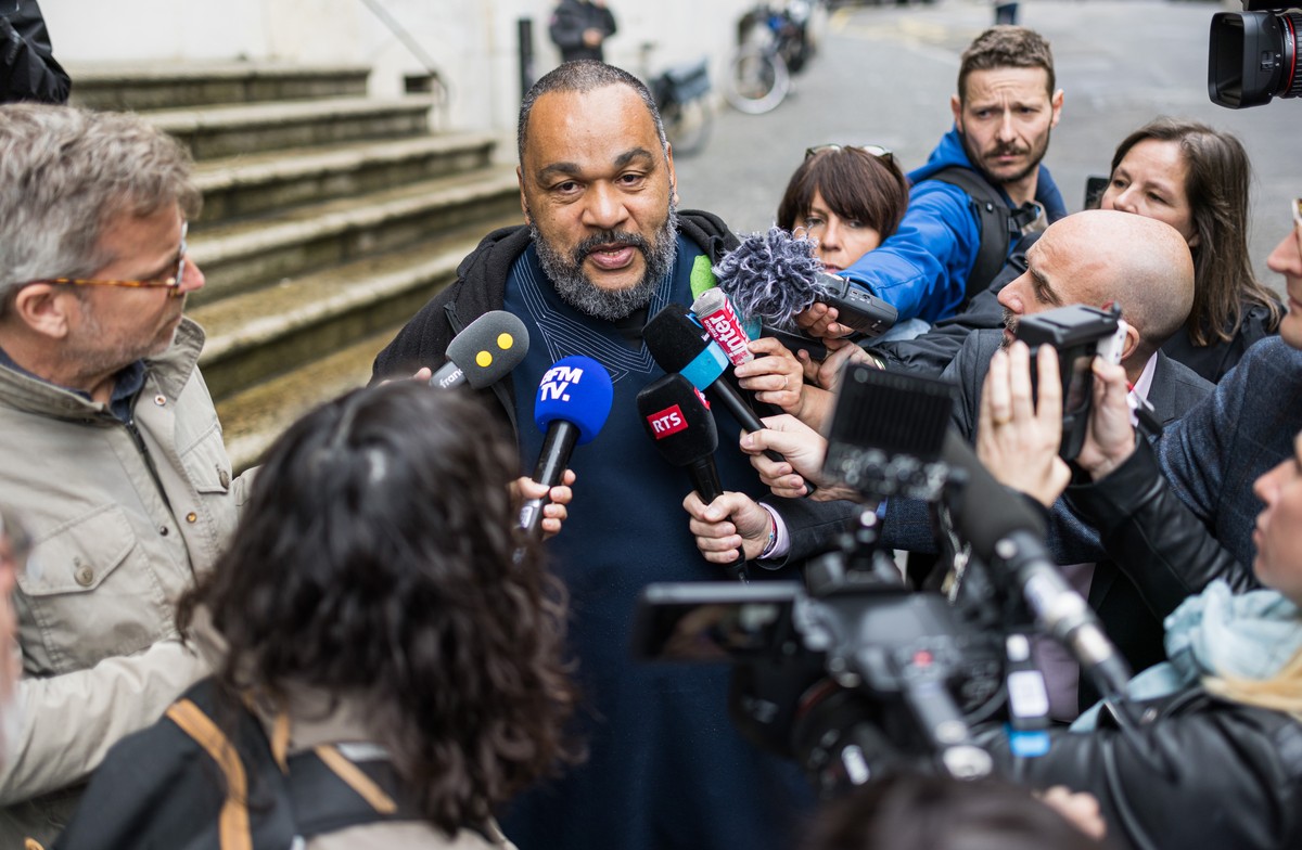 French controversial humorist Dieudonne MBala MBala speaks to the journalists after leaving the courthouse to testify at the Tariq Ramadan trial for a second day of hearing with Geneva's prosecut ...